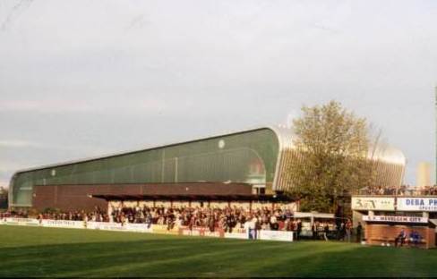 Stadion Wevelgem - Gegenseite, im Hintergrund die benachbarte Sporthalle, rechts einer der gemauerte Trainerbank-Unterstände